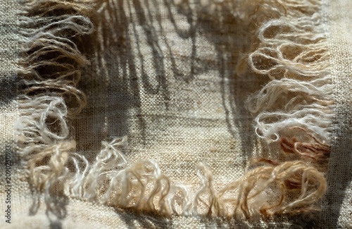 Extreme close up of frayed woven fabric edges filling entire frame loose threads earthy linen tones