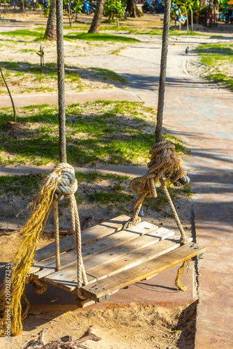 Wooden swing hanging on tropical beach paradise with ocean view Thailand.