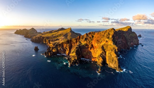 Golden hour illuminates rugged coastal cliffs and the deep blue ocean under a clear sky.