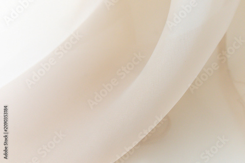 Soft delicate transparent organza, chiffon, silk fabric in cream, ivory, beige. Close up folds of fabric textile texture as background in champagne color with copy space.