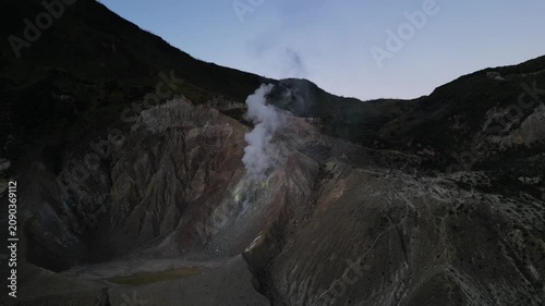 4k Drone video footage of the active crater of Mount Papandayan featuring rugged cliffs and sulfur-rich steam rising from volcanic vents in West Java, Indonesia.