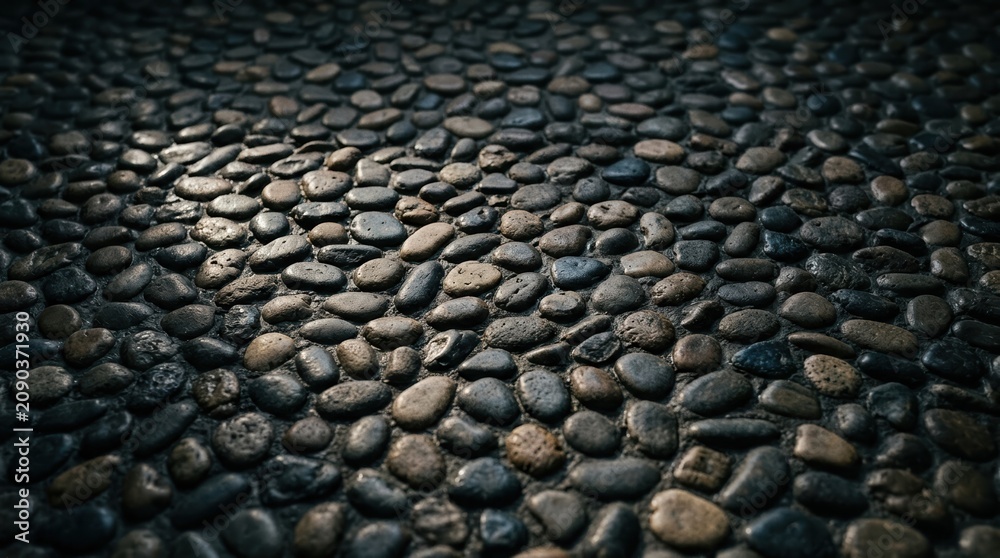 Naklejka premium Dark Cobblestone Path Texture Background Featuring Smooth Rounded River Stones for Garden Landscaping and Architectural Design Projects