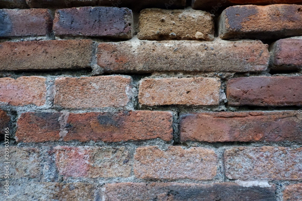 Fototapeta premium Weathered red brick wall with natural white efflorescence and aged texture, creating a rustic background for architectural and design projects.