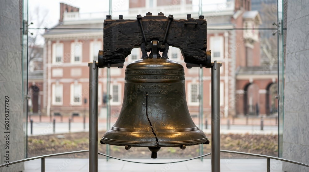 Obraz premium The iconic Liberty Bell with its famous crack displayed in a glass enclosure.