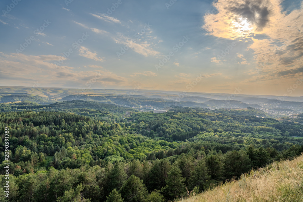 Obraz premium Layers of green mountains and hills in the haze during sunset. Panoramic View of Green hills and Meadow.