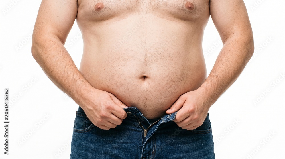 Naklejka premium A shirtless overweight man struggles to button his tight blue denim jeans because of his large belly while standing against a clean and bright white isolated studio background setting today.