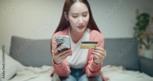 Close up of Asian woman hands holding credit card and smartphone for online shopping payment at home.