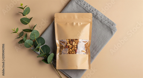 Minimalist kraft paper pouch mockup with window, organic food packaging on linen fabric, eco-friendly snack bag with eucalyptus branch
