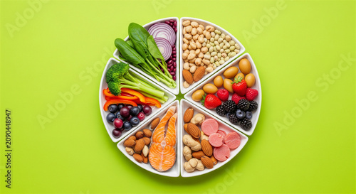 Healthy food plate chart with salmon and vegetables, balanced nutrition concept on green background, variety of fresh organic ingredients