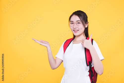 Smiling young student with backpack showing thumbs up and presenting copy space