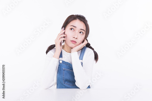 Thoughtful young woman talking on mobile phone at table