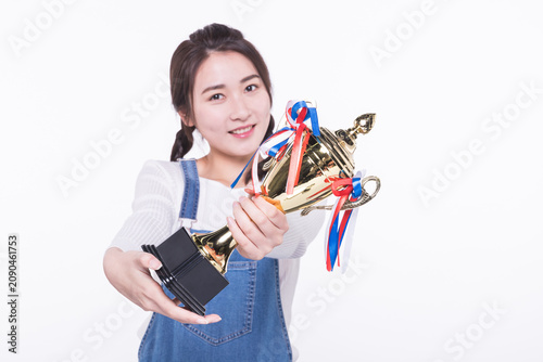 Smiling young woman holding trophy and celebrating achievement
