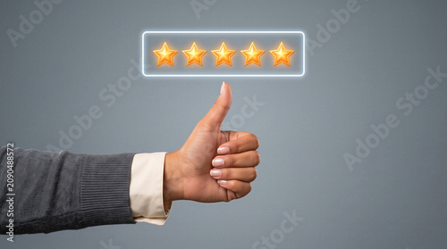 Thumbs up hand gesture with a five golden star rating, symbolizing excellent customer review, satisfaction and top quality