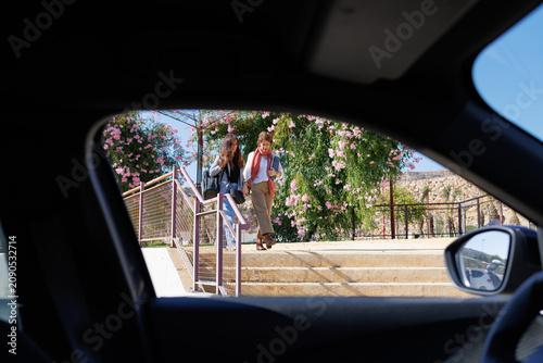 Fotografie Two women walking downstairs approaching car on sunny day
