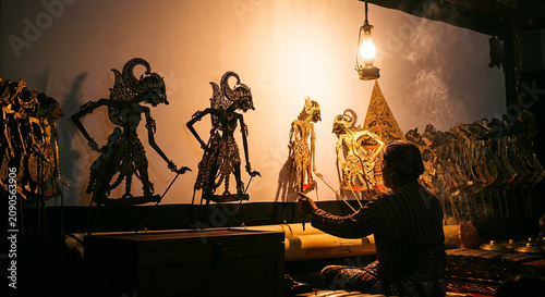 Traditional Indonesian shadow puppet wayang kulit performance with dalang puppeteer and lantern light