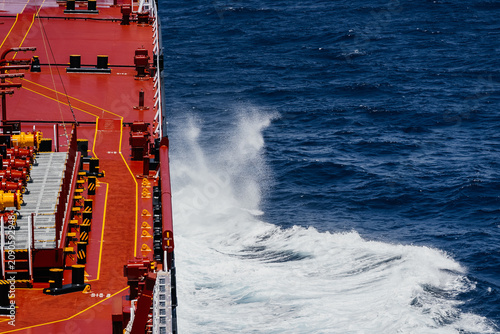 Tablou pe pânză A wave crashes against the side of a huge oil tanker sailing in open sea