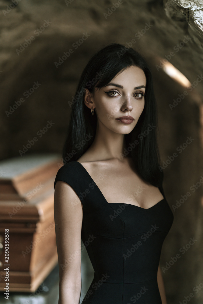 Fototapeta premium vampire woman with long raven hair in black dress, tall athletic female vampire portrait with hazel eyes, elegant gothic vampire with realistic skin and black dress