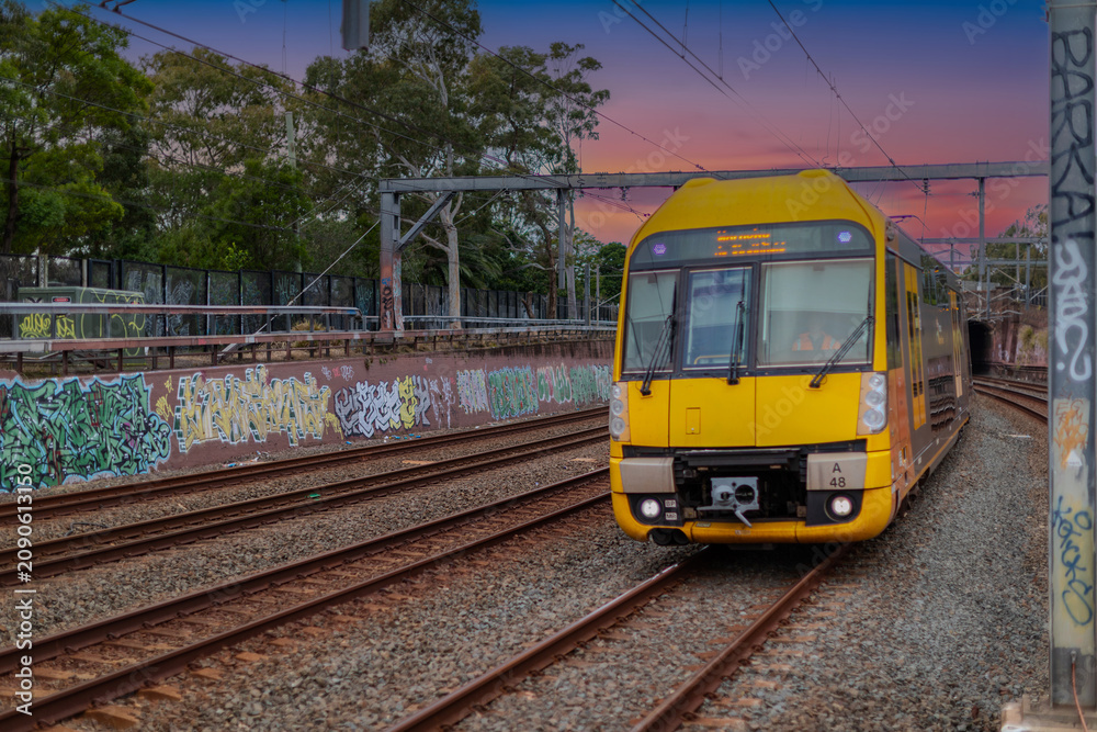 Fototapeta premium 7 July 2026 Passenger Train going through Lewisham Train Station at Sunset a suburban Sydney train Station in Sydney NSW Australia