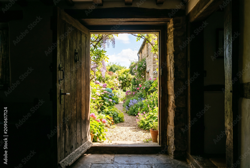 Fototapeta premium Doorway framing bright exterior garden view from dark interior