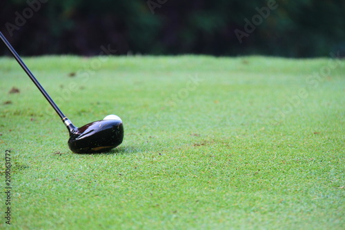 a black golf club driver positioned on a lush green turf