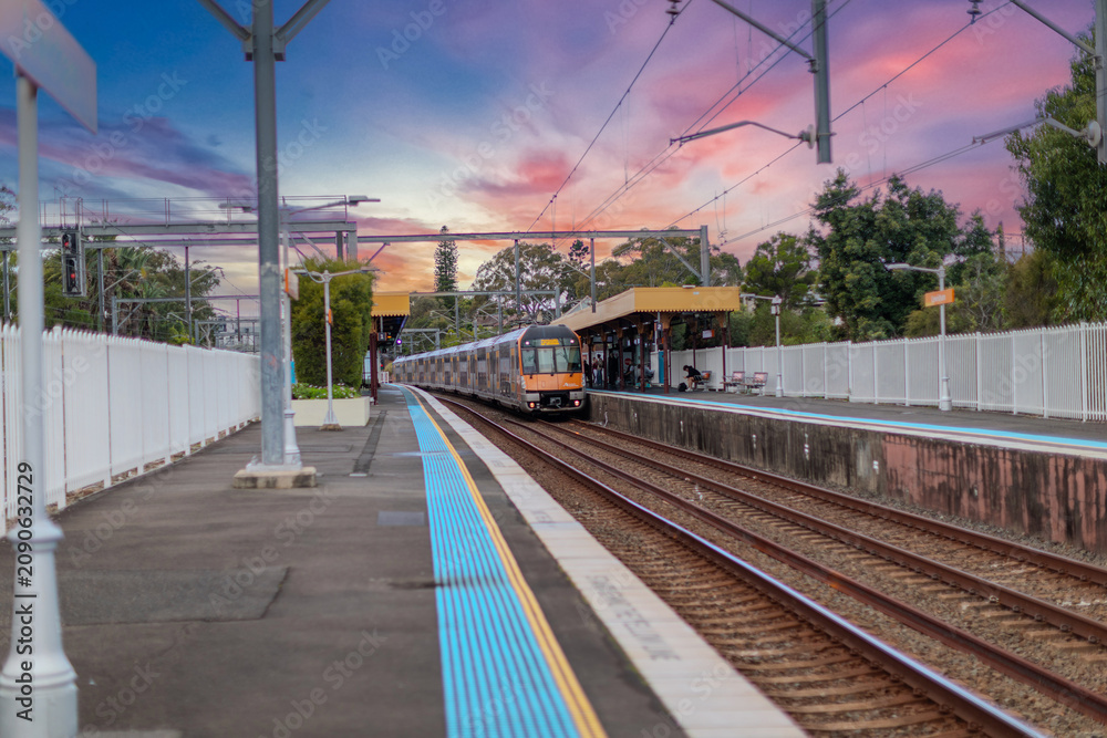 Fototapeta premium 7 July 2026 Passenger Train going through Lewisham Train Station at Sunset a suburban Sydney train Station in Sydney NSW Australia