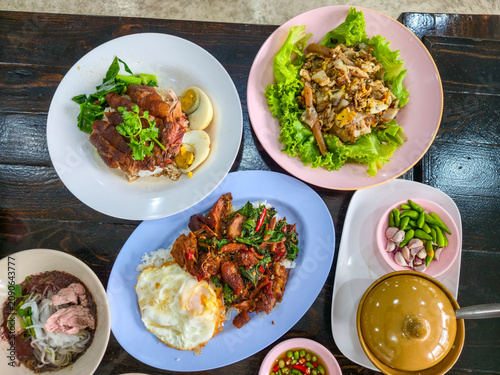 A dining table filled with authentic Thai dishes, including noodles, rice, and a variety of traditional foods, ready to enjoy.