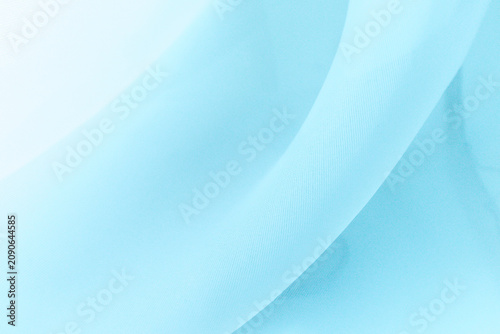 Soft delicate transparent organza, chiffon, silk fabric in light blue. Close up folds of fabric textile texture as background in pastel blue color with copy space.