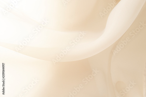 Soft delicate transparent organza, chiffon, silk fabric in cream, ivory, beige. Close up folds of fabric textile texture as background in champagne color with copy space.