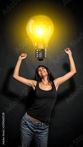 Joyful Young Woman Celebrating Beneath Glowing Light Bulb on Dark Background