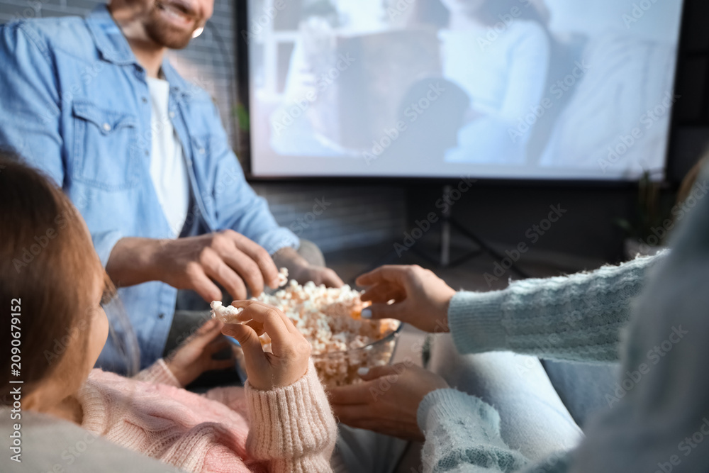 Obraz premium Family eating popcorn while watching movie at home