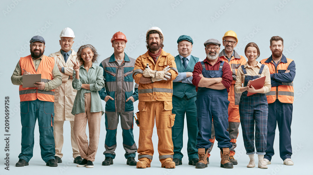 Fototapeta premium Industrial workers pose together in professional uniforms for a portrait against a gray backdrop.