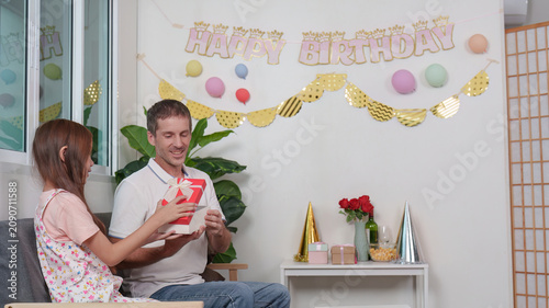 Φωτογραφία Happy father receiving birthday gift from daughter at home celebration