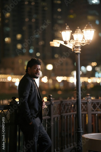 Foto Well-Dressed Young Man Standing Near Burj Khalifa in Downtown Dubai at Night