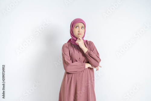 Pensive Young Asian Muslim Woman Wearing Pink Hijab And Dress Looking Thoughtful Against White Background