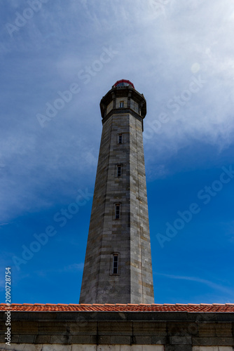 Imposing low angle perspective of the historic stone Phare des Baleines lighthouse towering into a bright blue sky on the Ile de Re, France.