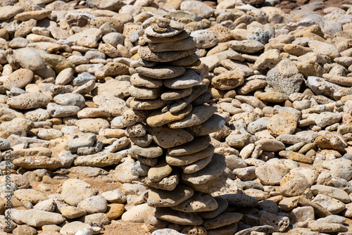 A carefully balanced stone cairn standing on a bright, dry rocky beach during a sunny summer day on the beautiful Ile de Re in France.