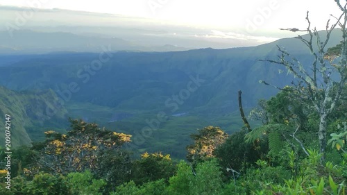 Majestic sunrise over an expansive mountain valley, revealing a breathtaking natural landscape with lush greenery and distant peaks under a soft, ethereal sky