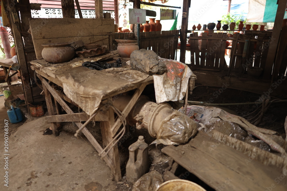Obraz premium Traditional Clay Pottery Workshop with Rustic Wooden Workbench and Earthenware