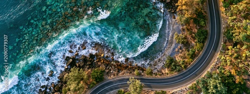 Aerial top view of a scenic coastal road next to the turquoise ocean and rocks.