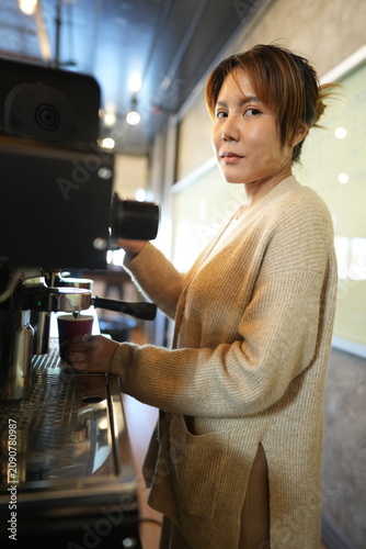 фотографія Young barista tamping fresh coffee compacts the coffee grounds with a steady tam