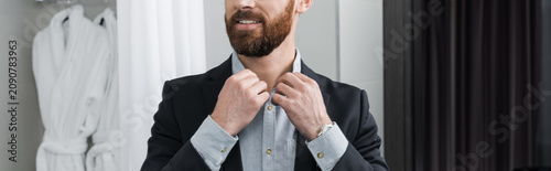 Cuadro en lienzo Elegant young man adjusts his dapper suit in a luxury hotel suite before a speci