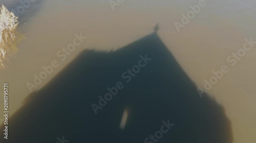 Aerial view old, abandoned  church in Aparan rezervior in Armenia, West Asia.  The structure reflects in the water. Green hills surround the area. The weather is sunny. The location shows signs of nat