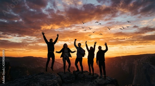 Group of Friends Celebrating Success on Mountain Summit at Sunset.
