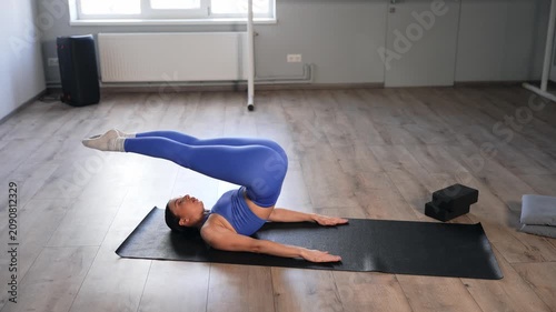Flexible sporty fit attractive woman practicing yoga plow pose exercise on fitness mat, stretching spine , shoulder and leg muscles, improving flexibility and core strength in health club.