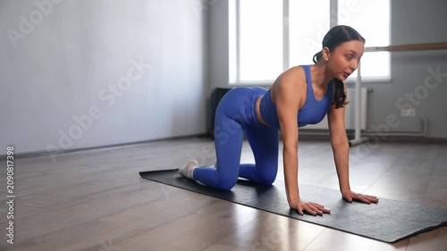 Elegant active fit charming woman in sportswear doing yoga stretches on exercise mat, practicing child's pose to cobra flow, improving flexibility and overall body balance in fitness studio.