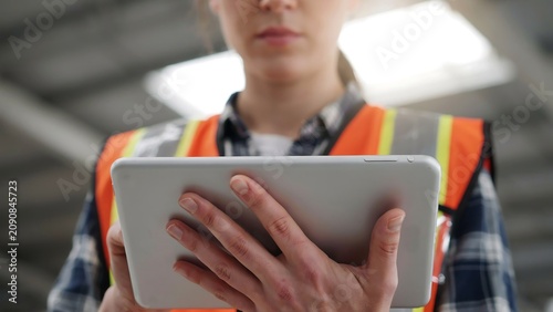 Warehouse worker wearing high visibility safety vest using digital tablet