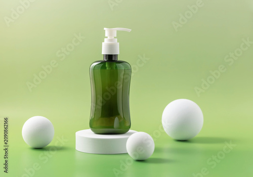 Bottle with pump dispenser rests on a white podium next to white balls on a green background