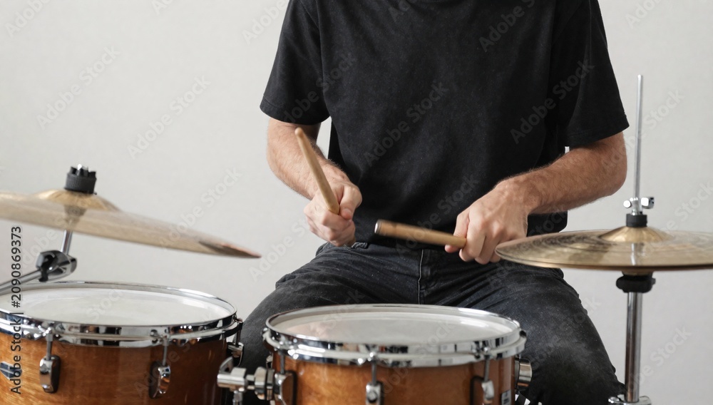 Fototapeta premium Torso shot of a drummer performing on a drum set with drumsticks in a studio setting