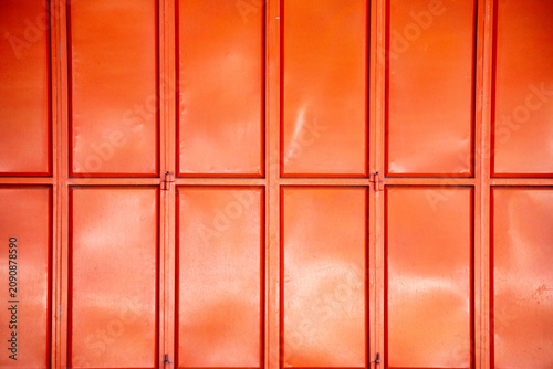 Schilderij op canvas Folding metal doors feature a repeating grid pattern made of orange-painted steel plates and frames