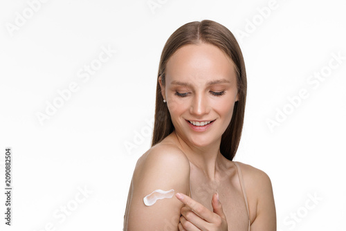 Young Woman applying sunscreen cream or cosmetic moisturizing lotion on perfect hydrated skin on shoulder